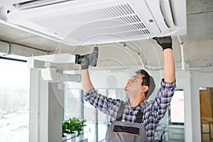 Portrait of young male indian technician repairing air conditioner. Air conditioner repairs.