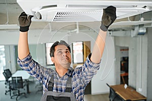 Portrait of young male indian technician repairing air conditioner. Air conditioner repairs.