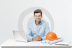 Portrait of young male interior designer or engineer smiling while sitting on his office table.