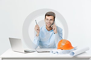 Portrait of young male interior designer or engineer smiling while sitting on his office table.