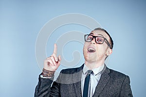 Portrait of a young male nerd in glasses and in a stylish suit points with his fingers