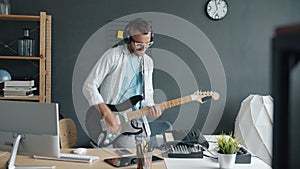 Portrait of young male performer practicing with electric guitar playing at home