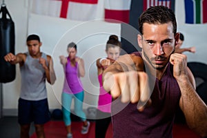 Portrait of young male practicing boxing against flags