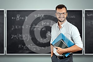 Portrait of a young male teacher on the background of the school blackboard. Teacher`s Day Knowledge Day back to school study