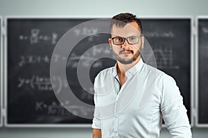 Portrait of a young male teacher on the background of the school blackboard. Teacher`s Day Knowledge Day back to school study