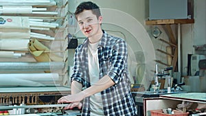 Portrait of a young male worker, smiling and talking to a camera in workshop