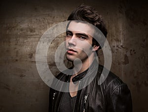 Portrait of a young man against the background of a metal wall with free space