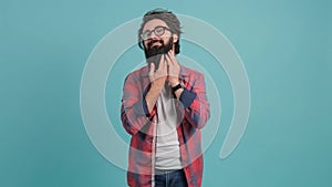 Portrait of a young man arranging his beard and looking at the camera.