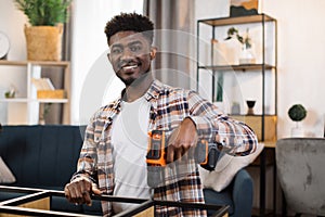 Portrait of young man assembling furniture at home