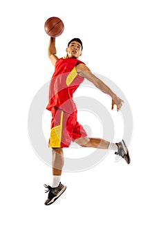 Portrait of young man, basketball player jumping, training, throwing ball into basket isolated over white studio