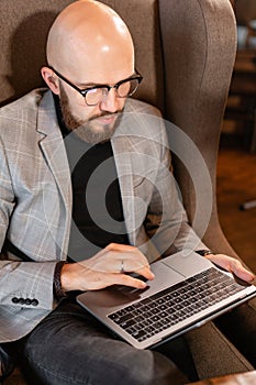 Portrait of young man with beard in the glasses looking to the monitor laptop. Successful people, businessman in