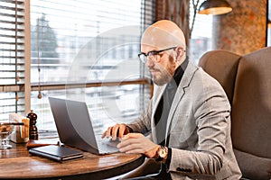 Portrait of young man with beard in the glasses looking to the monitor laptop. Successful people, businessman in