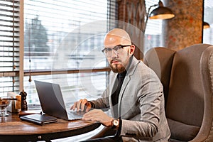 Portrait of young man with beard in the glasses looking to the monitor laptop. Successful people, businessman in