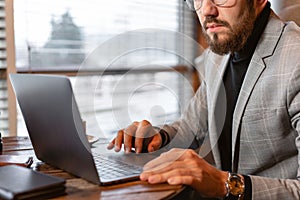 Portrait of young man with beard in the glasses looking to the monitor laptop. Successful people, businessman in