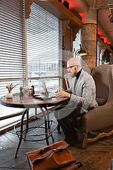 Portrait of young man with beard in the glasses looking to the monitor laptop. Successful people, businessman in