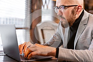 Portrait of young man with beard in the glasses looking to the monitor laptop. Successful people, businessman in