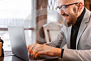 Portrait of young man with beard in the glasses looking to the monitor laptop. Successful people, businessman in