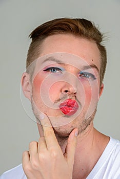 Portrait of young man with beard stubble wearing makeup