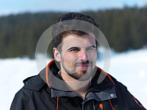 Portrait of young man with beard and sunglasses on fresh snow