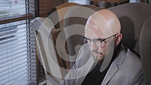 Portrait of young man with beard, wearing a suit in the glasses looking to the monitor laptop. Successful people