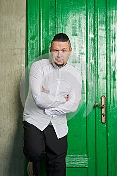 Portrait of a young man, in black slacks and white shirt, green door photo