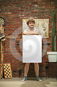 Portrait of young man with blank sign like social media screen sitting at home.