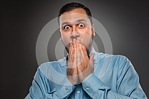 Portrait young man in blue shirt, looking with amazement