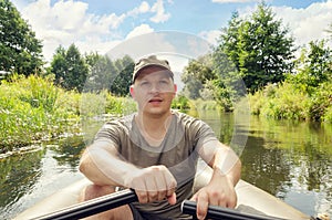 Portrait of a young man in a boat with oars outdoors