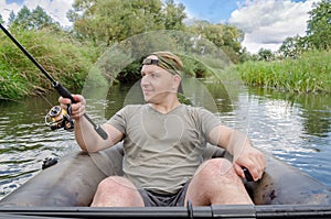 Portrait of a young man in a boat with a spinning rod