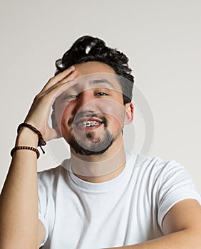 Portrait of a young man with braces smiling. A happy young man with braces on a white background