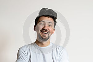 Portrait of a young man with braces smiling and laughing. A happy young man with braces on a white background