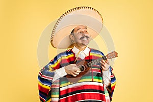 Portrait of young man in bright garment, poncho isolated over yellow background