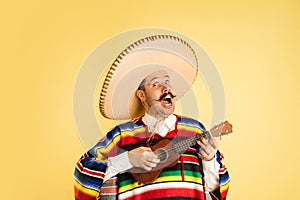 Portrait of young man in bright garment, poncho isolated over yellow background