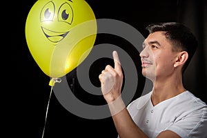 Portrait of a young man in a business suit and wigh with balloons. Positive guy posing in the studio