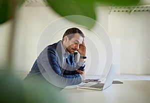 Portrait of young man, businessman, employee sitting in despair at the table with laptop and thinking. End of business