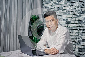 Portrait of young man businessman working  at  office with laptop on desk, looking at camera, smiling