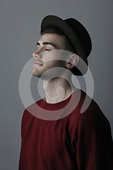 Portrait of a young man with closed eyes standing against grey background