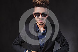 Portrait of young man closing his jacket while posing in dark s