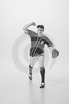 Portrait of young man, concentrated baseball player, pitcher in a glove serving ball. Black and white photography