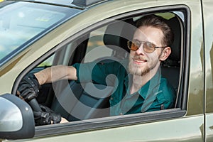 Portrait of a young man in dark glasses driving a car