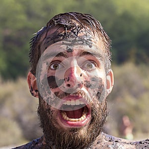 Portrait of a young man with a dirty smudge with a beard on the nature in summer day