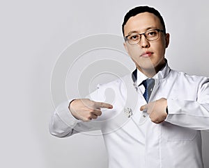 Portrait of young man doctor urologist or proctologist showing pointing at special medical sign on his gown uniform