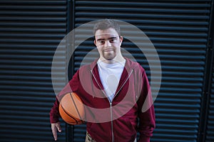 Portrait of young man with down syndrom holding basketball ball.