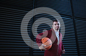 Portrait of young man with down syndrom holding basketball ball.