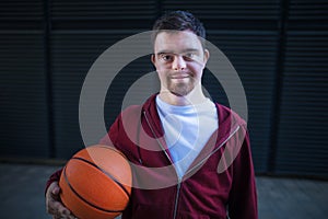 Portrait of young man with down syndrom holding basketball ball.