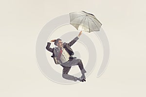 Portrait of young man dressed in 50s, 60s style with umbrella isolated on white background. Concept of culture, art