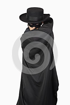 Portrait of young man dressed as Zorro against gray background photo