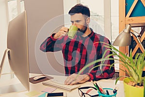 Portrait of young man drinking coffee and typing on keyboard