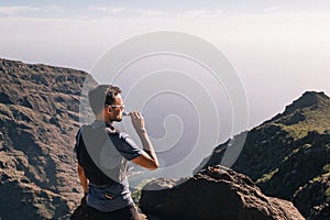 Portrait of young man drinking energy sports nutrition energy gel while sitting and resting after trail running