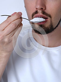 Portrait of a young man eating sugar with a spoon close up